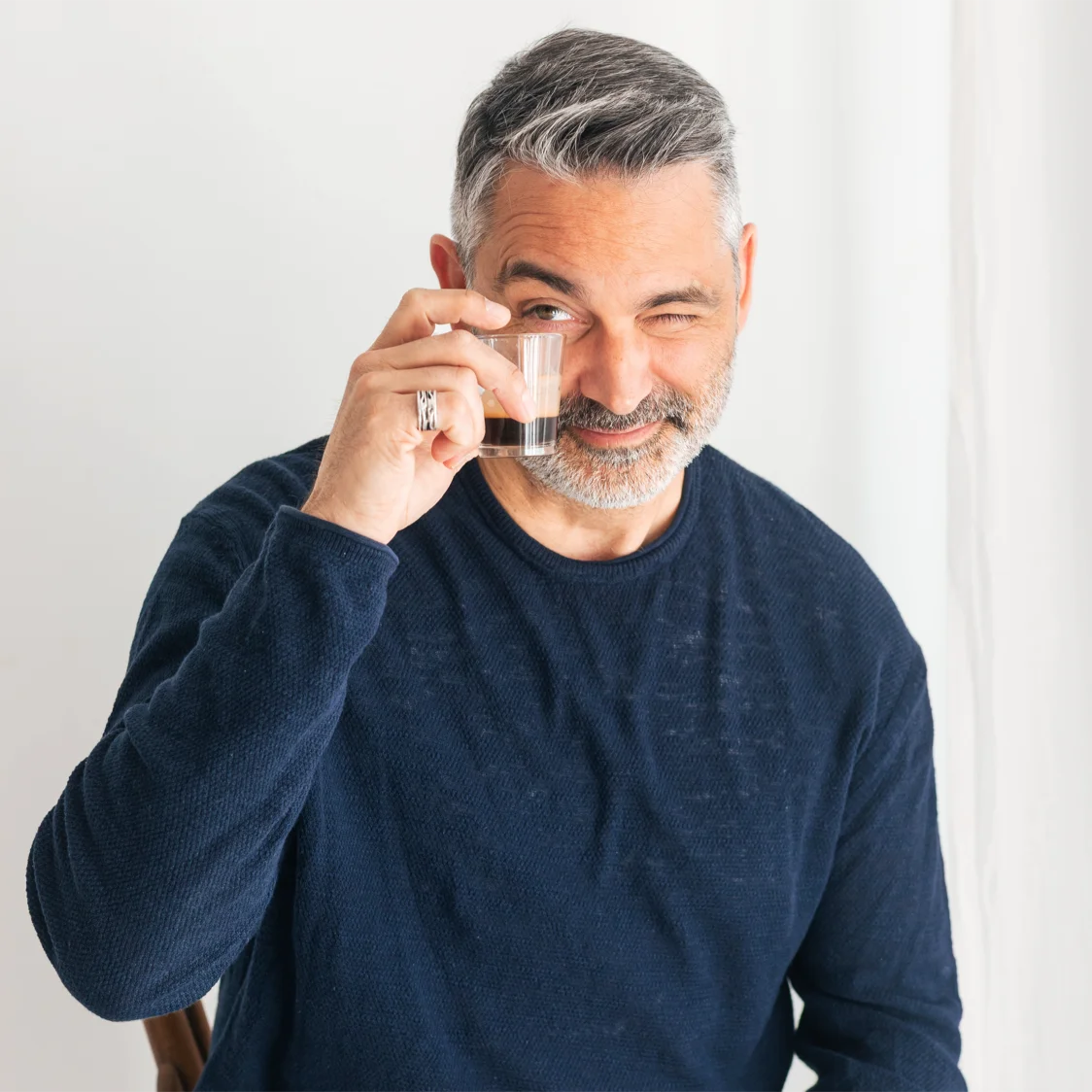 Leadership-Trainer Lars Rättig sthet vor einem hellen Hintergrund, mit einem Espresso in der Hand und lächelt freundlich in die Kamera