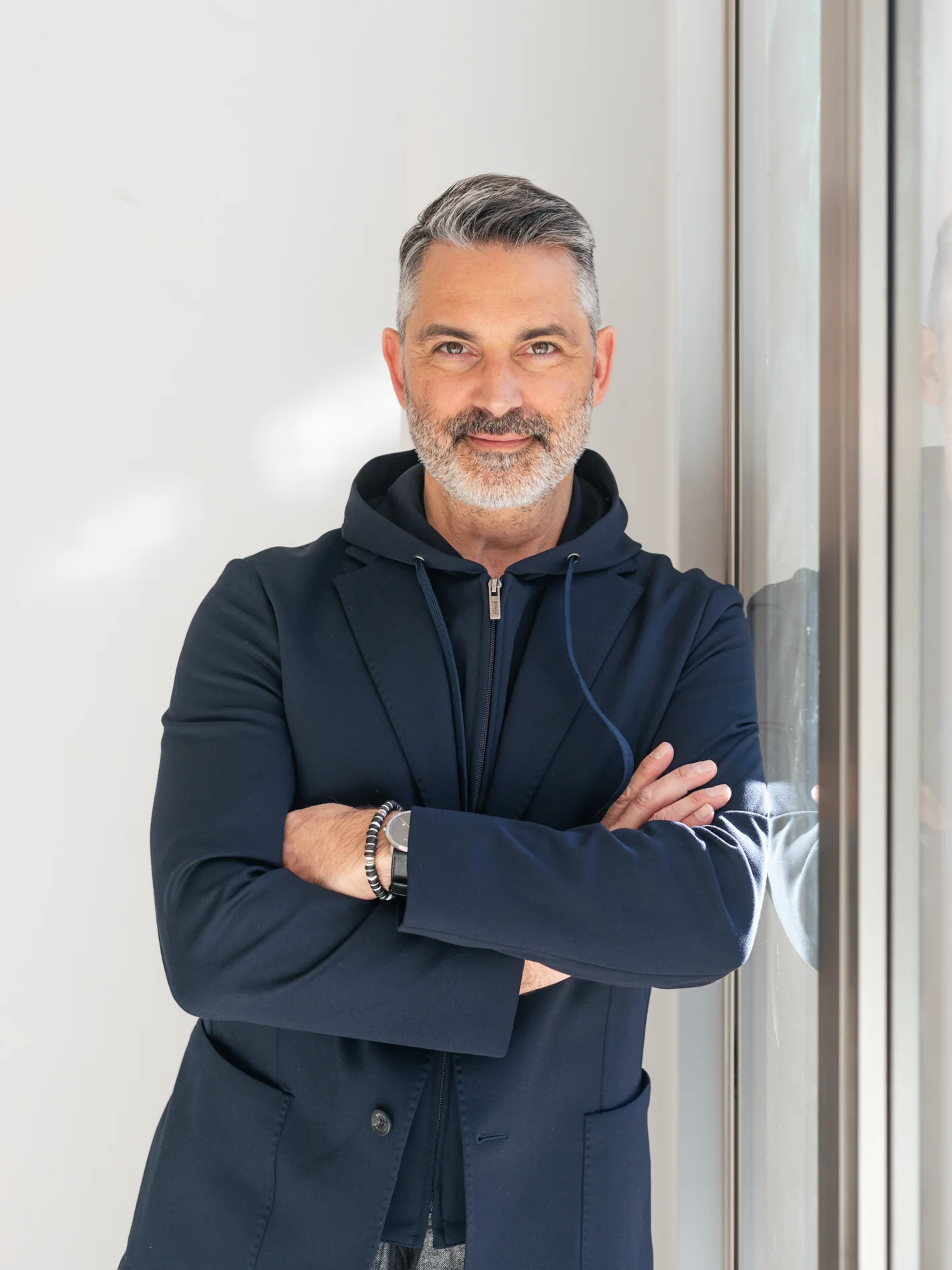 Leadership-Trainer zeigt Lars Rättig, Profi in Führung, Beratung und Vertrieb, er steht lässig an eine Wand gelehnt, die Arme verschränkt und schaut freundlich in die Kamera.